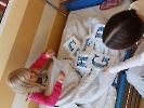Dziewczynki siedzące przy łóżku. Na łóżku rozłożone kartki z wróżbami andrzejkowymi.