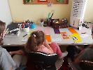 Dzieci siedzące przy stole, przed nimi na stole kolorowe karteczki z wróżbami.