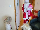 Mikołaj wchodzi do sali dziecka, w ręku trzyma prezent, różową lalkę.