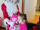 Mikołaj wręcza dziewczynce lalkę.